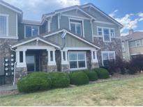 Charming two-story home with a stone facade, light green siding, manicured bushes, and a covered front porch at 9768 Mayfair St # E, Englewood, CO 80112
