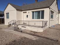Charming single-story home featuring a cozy front porch with decorative metal railing and neutral stucco exterior at 698 S 2Nd Ave, Brighton, CO 80601