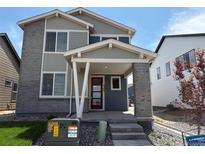 Inviting home with a covered front entrance and a stylish, modern front door, brick pillars, and gray and blue siding at 2283 Serenidad St, Brighton, CO 80601