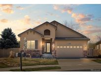 Charming single-story home featuring stucco siding, stone accents, manicured lawn, and a two-car attached garage at 418 Rifle Ct, Broomfield, CO 80020