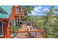 Beautiful outdoor deck with mountain views, lounge seating, dining area, and railing at 10390 Hondah Dr, Littleton, CO 80127