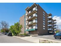 Brick apartment building featuring multiple balconies, front entrance, and manicured landscaping at 1265 Elizabeth St # 305, Denver, CO 80206