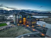 Beautiful exterior shot of the house with mountain views at dusk with manicured lawn and mature landscaping at 8727 Hunters Hill Ln, Littleton, CO 80125