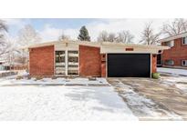 Charming red brick home featuring an attached garage and snowy front yard at 2670 S Raleigh St, Denver, CO 80219