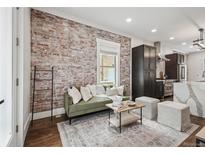 Cozy living room features exposed brick wall, modern furnishings, and hardwood floors at 1024 W 8Th Ave, Denver, CO 80204