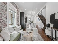 Inviting living room boasts exposed brick wall, modern furnishings, and staircase to the second floor at 1024 W 8Th Ave, Denver, CO 80204