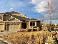 Charming townhome with stone accents, a well-manicured lawn, and a two-car garage on a sunny day at 22435 E Plymouth Cir, Aurora, CO 80016