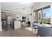 Open floor plan with modern kitchen, living room with fireplace, and adjacent dining area with natural light at 5026 S Platte River Pkwy, Littleton, CO 80123