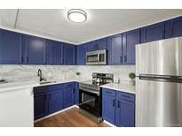 Modern kitchen boasting stainless steel appliances, sleek countertops, and dark blue cabinets at 3047 W 47Th Ave # 607, Denver, CO 80211