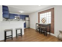 Bright kitchen boasts stylish blue cabinets, modern appliances, breakfast bar and eat-in area near the window at 3047 W 47Th Ave # 607, Denver, CO 80211
