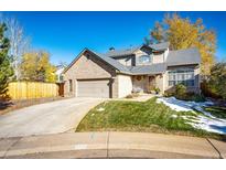 Charming two-story brick home with a well-maintained lawn and a two-car garage on a sunny day at 6454 S Nelson Way, Littleton, CO 80127
