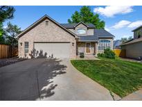 Charming brick home featuring a well-manicured lawn and a spacious two-car garage at 6454 S Nelson Way, Littleton, CO 80127