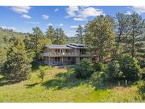 Inviting home with a sprawling deck nestled amongst mature trees and natural landscaping at 5073 N Lariat Dr, Castle Rock, CO 80108
