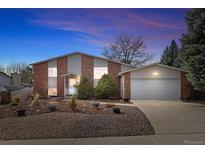 Charming split-level home featuring a two-car garage and well-maintained front yard at dusk at 7325 Taft Ct, Arvada, CO 80005