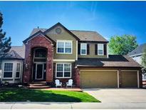 Charming two-story home featuring a manicured lawn, brick accents, and a welcoming front porch at 822 Shadowstone Dr, Highlands Ranch, CO 80129