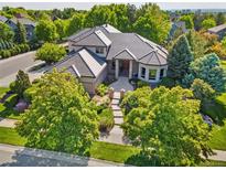 Stunning home featuring lush landscaping, a courtyard entry, and elegant architectural details on a sunny day at 5350 S Marshall St, Littleton, CO 80123