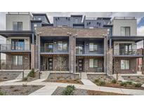 Modern townhomes featuring brick and siding exteriors, private balconies, and landscaped front yards at 9645 Browns Peak Cir, Littleton, CO 80125