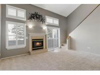 Bright living room with a cozy fireplace, neutral carpet, many windows, and access to the upper floors at 1847 S Union Blvd, Lakewood, CO 80228