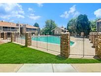 A well-maintained community pool surrounded by lush green lawns and a decorative stone fence, perfect for relaxation at 8225 Fairmount Dr # 106, Denver, CO 80247