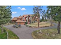 Luxury home with stone and wood exterior, expansive windows, and a large driveway at 28940 Pinewood Vista Dr, Evergreen, CO 80439