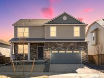 Charming two-story home featuring stone accents, neutral siding, and a well-manicured front yard at 6132 Hourglass Dr, Brighton, CO 80601