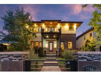 Stunning two-story home featuring a balcony, modern architectural details, and manicured landscaping at dusk at 1344 S Saint Paul St, Denver, CO 80210
