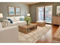 Bright living room featuring a white sofa, wood coffee table, area rug, and access to a balcony at 7755 E Quincy Ave # 203A6, Denver, CO 80237