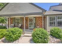 Charming brick home featuring a cozy front porch with inviting seating and a decorative floral wreath on the front door at 6792 E Briarwood Dr, Centennial, CO 80112