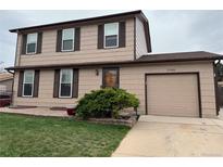 Charming two-story home with a tan exterior, brown trim, and a well-manicured front yard at 17882 E Wyoming Pl, Aurora, CO 80017
