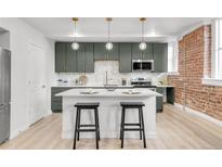 Modern kitchen boasts an island with seating, gray cabinets, updated appliances, and stylish pendant lighting at 1210 E Colfax Ave # 104, Denver, CO 80218