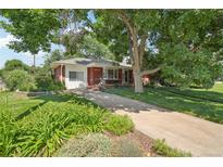 Charming brick home featuring a well-manicured front yard with mature trees, and inviting curb appeal at 4895 S Galapago St, Englewood, CO 80110