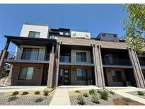 Modern townhomes with brick facade, private balconies, and manicured landscaping under a clear blue sky at 8321 Mount Kataka St, Littleton, CO 80125