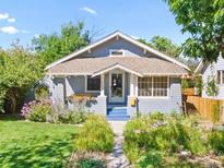 Charming blue bungalow with a well-manicured lawn and lush flowerbeds leading to the front door at 4429 Winona Ct, Denver, CO 80212