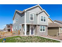 Charming two-story home features stone accents, light gray siding and a well-manicured lawn at 803 N Bently St, Watkins, CO 80137