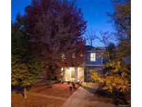 Charming two-story home with a well-maintained front yard and colorful trees at dusk at 3674 Dexter St, Denver, CO 80207