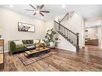 Inviting living room features a plush green sofa, modern ceiling fan, and stylish decor at 18077 E 99Th Ave, Commerce City, CO 80022