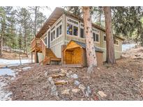Charming home featuring a wooden porch, large windows, and lush surroundings at 30690 Highway 72, Golden, CO 80403