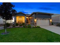 Charming home showcasing a lush lawn, stone accents, and inviting front porch, illuminated against a twilight sky at 22978 E Bailey Cir, Aurora, CO 80016