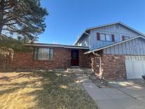 Charming brick home featuring a well-maintained yard, attached garage, and eye-catching red door at 15147 E Floyd Ave, Aurora, CO 80014