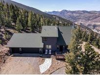 Aerial view of gray home with two car garage surrounded by mountains at 538 Sawmill Creek Rd, Evergreen, CO 80439