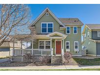 Charming two-story home with a welcoming front porch and a well-maintained yard under a clear blue sky at 9435 E 108Th Pl, Commerce City, CO 80640
