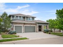 Beautiful two-story home featuring stone accents, gray siding, three-car garage, and professionally landscaped front yard at 4421 Tanager Trl, Broomfield, CO 80023