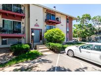 Two-story apartment building with updated red trim and lush landscaping at 12131 Melody Dr # 101, Denver, CO 80234