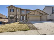 Beautiful two-story home with a stone and siding exterior, three-car garage, and landscaped front yard at 9559 Yucca Way, Arvada, CO 80007