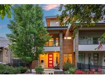 Modern two-story home with stone accents, a red front door, and a small balcony overlooking the landscaped front yard at 3845 N Raleigh St, Denver, CO 80212