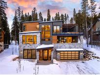 Modern two-story home featuring a stone and wood facade, balcony, and a snow-covered driveway at 27 Boulder Cir, Breckenridge, CO 80424