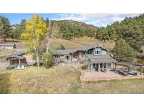 Charming home exterior with a stone patio, pergola, and lush trees at 20 W Ranch Trl, Morrison, CO 80465
