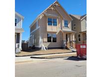 Tan two-story home with charming architectural details and an inviting front porch, awaiting landscaping at 223 Washington St, Erie, CO 80516