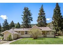 Charming single-story home with a covered front porch, mature trees, and well-maintained landscaping at 10049 S Turkey Creek Rd, Morrison, CO 80465