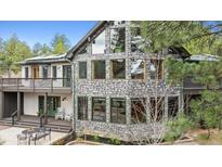 Striking stone house featuring many windows, a deck, and a covered porch with outdoor seating at 7317 Fremont Pl, Larkspur, CO 80118